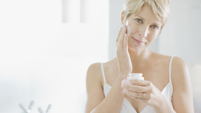 woman putting on moisturizer