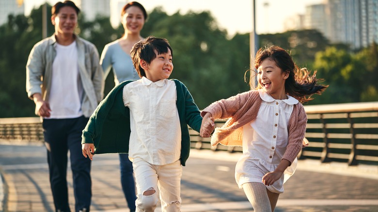 a family of four walking and playing in the park