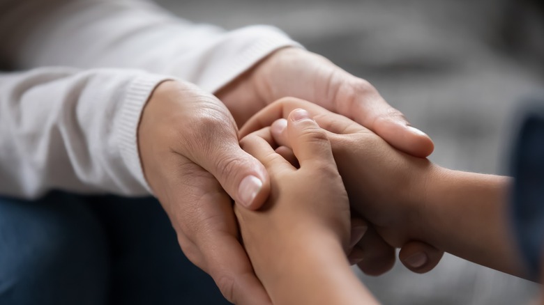 a parent holding the hands of their child