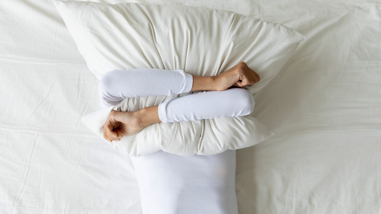 Man in bed gripping pillow
