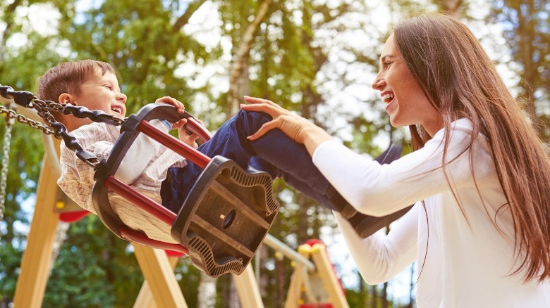 Woman pushing child on swing