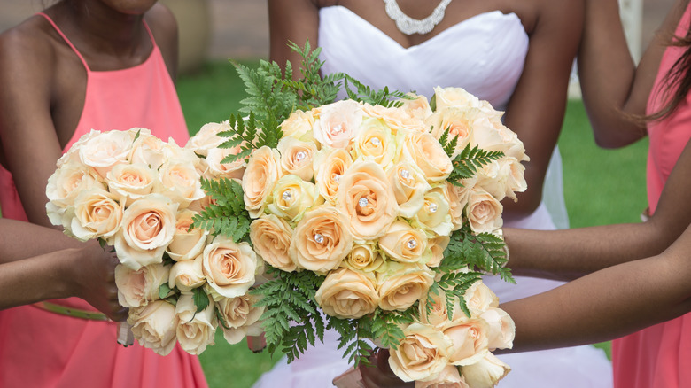 Bridal party holding up bouquets outdoors