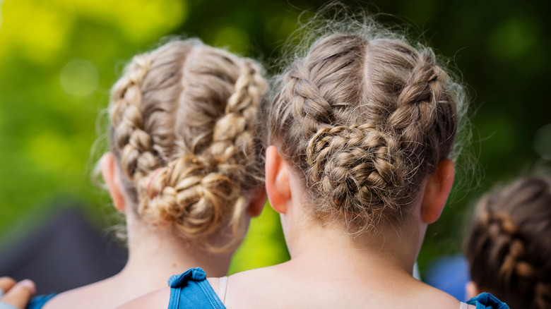 Two women with braided hair in buns standing