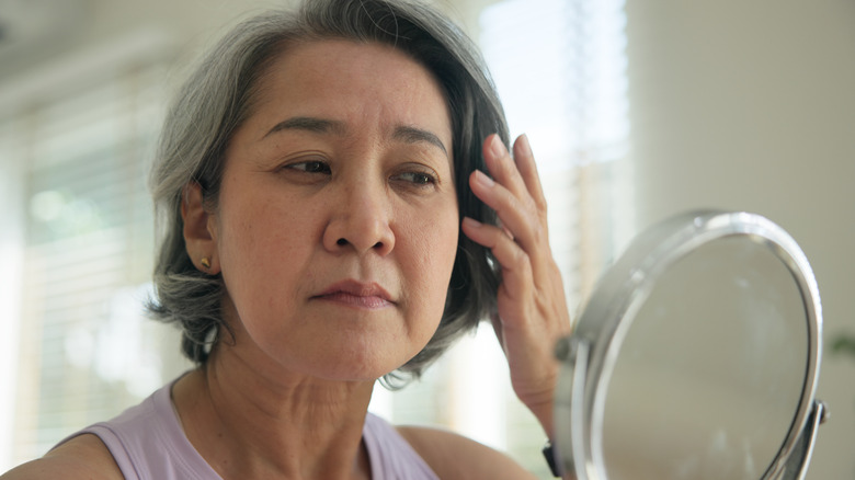 A woman admiring her Botox work around her crows feet in the mirror