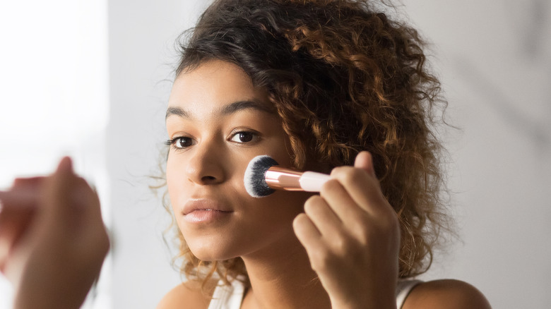 woman applying blush to face
