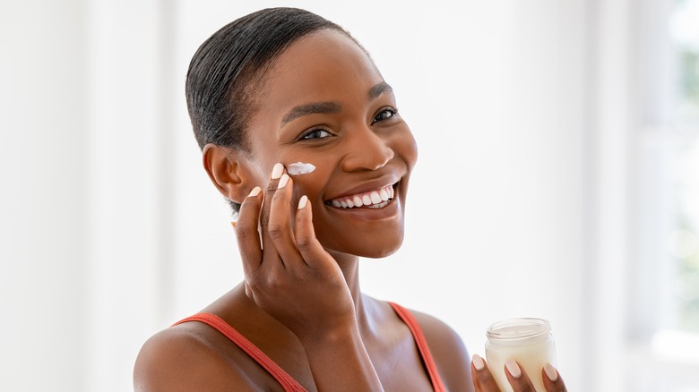 Smiling woman applying cream