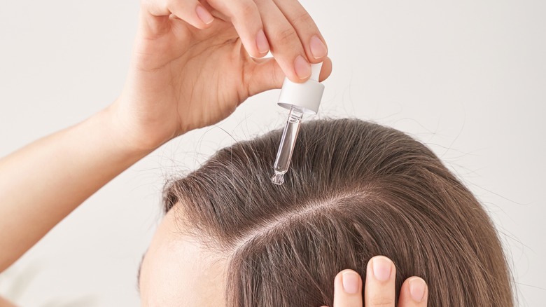 woman applying serum in hair 