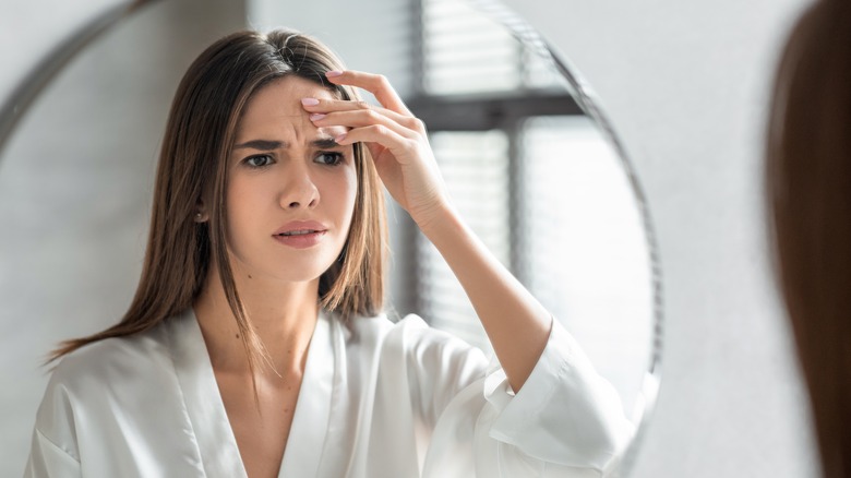 Unhappy woman checking her face on mirror