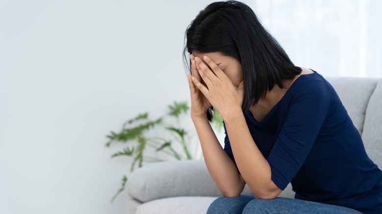 Woman sits with head in hands