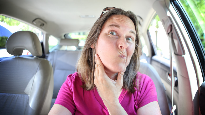 woman checking face in mirror