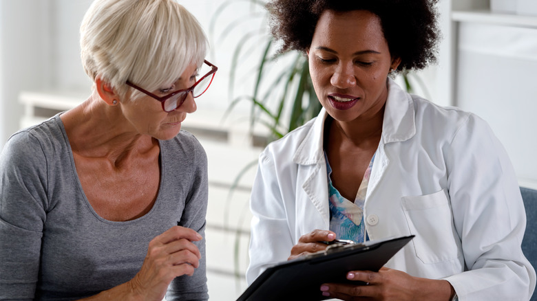 doctor looks at chart with patient