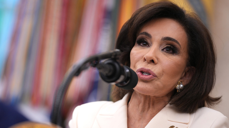 Jeanine Pirro talking into a microphone with Donald Trump behind her