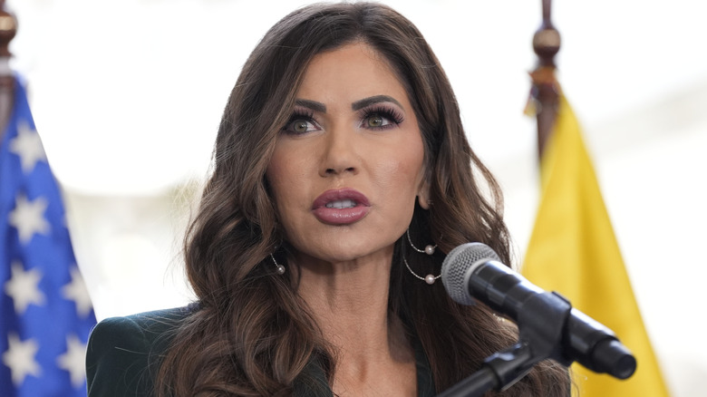 ﻿Kristi Noem, post lip-fillers, photographed while speaking at ﻿a press briefing with Ecuador's Minister while wearing a suit