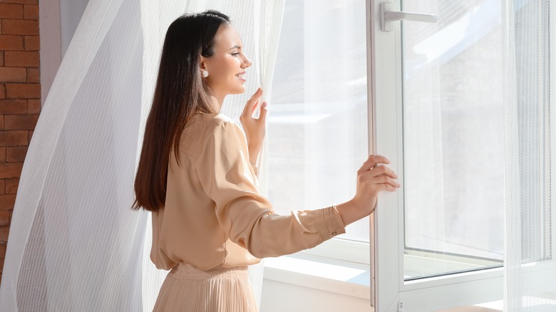 smiling woman opening window