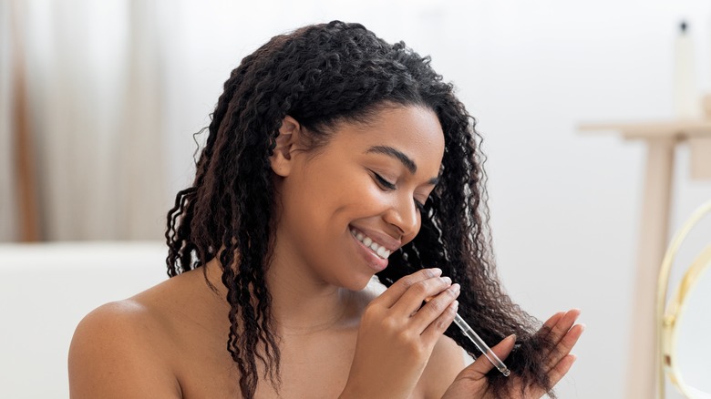 Woman putting oil on curly hair