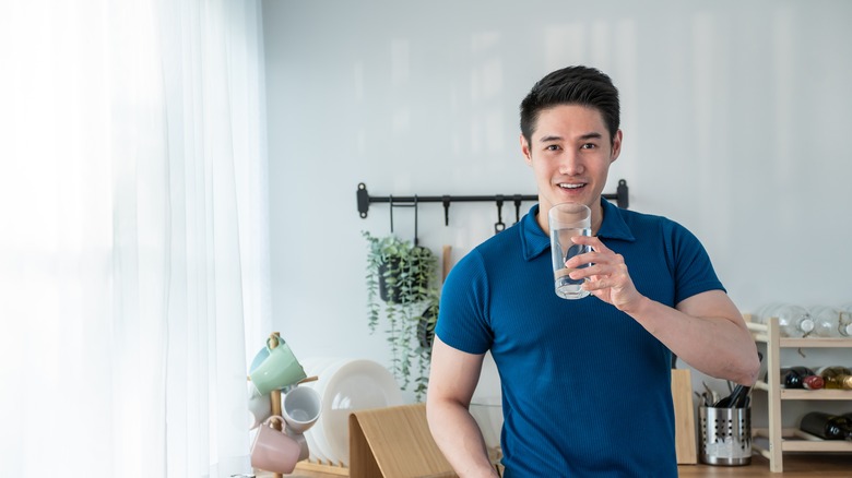 man drinking water in kitchen