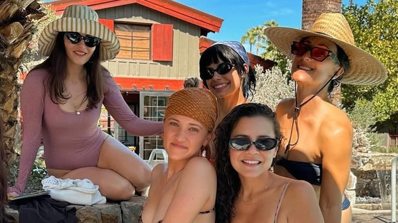 Emily Osment posing in a bathing suit while hanging out poolside with some friends