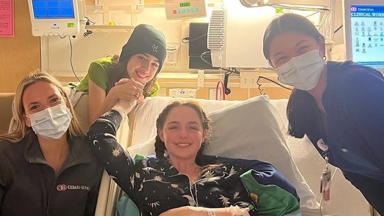 Mckenna Grace in a hospital bed smiling while surrounded by hospital staff