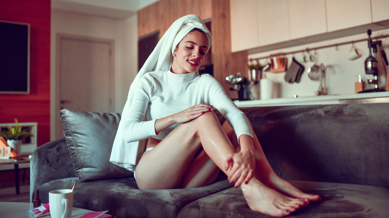 A woman moisturizing in her living room