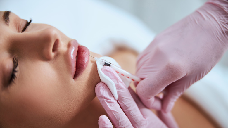 Doctor administering lip filler to patient's lower lip