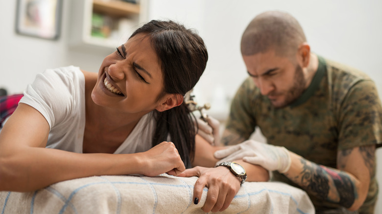 Woman in pain during tattooing