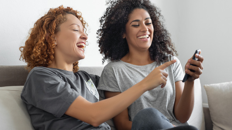 women on couch holding phone