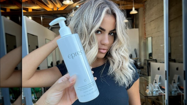 Hairstylists holds bottle of epres