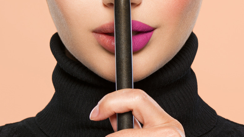 Half-done lips behind makeup brush
