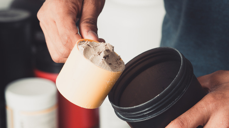 Person pouring whey protein into shaker