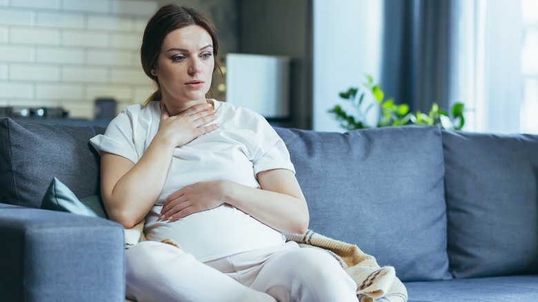 woman holding throat and tummy