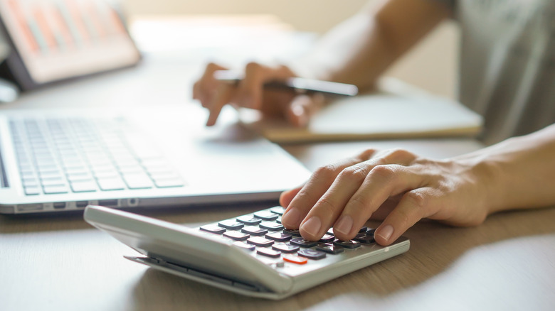Person with a laptop and calculator