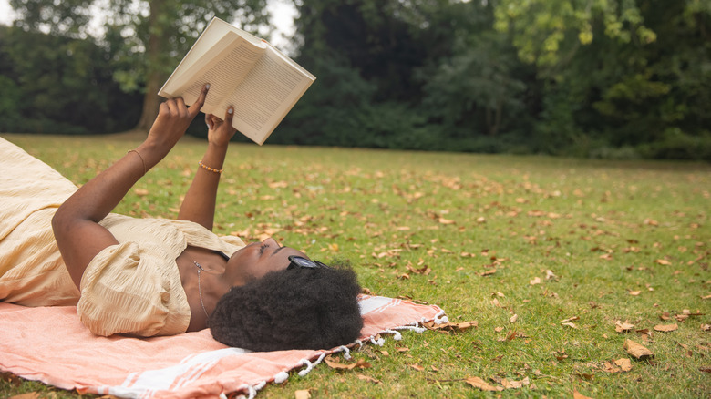 A woman reading a book on the grass