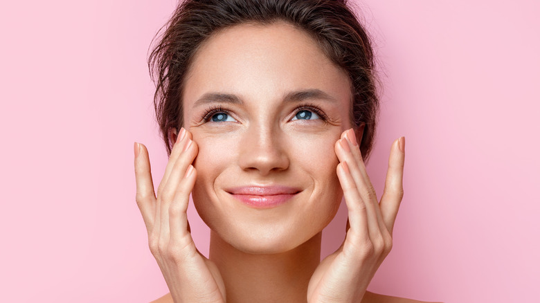 woman smiling touching her face