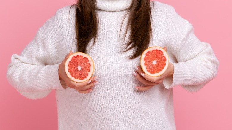 Woman holding fruit on chest
