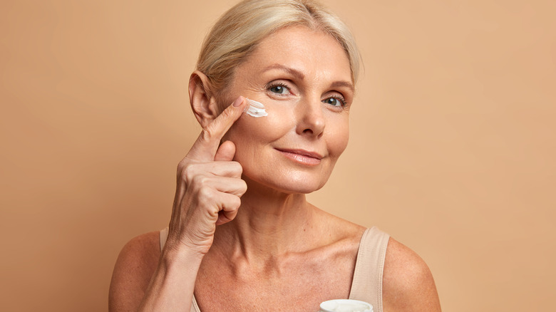 woman applying cream on face