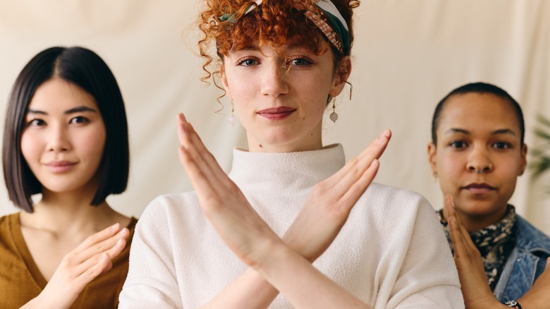 Three people making "X" arms