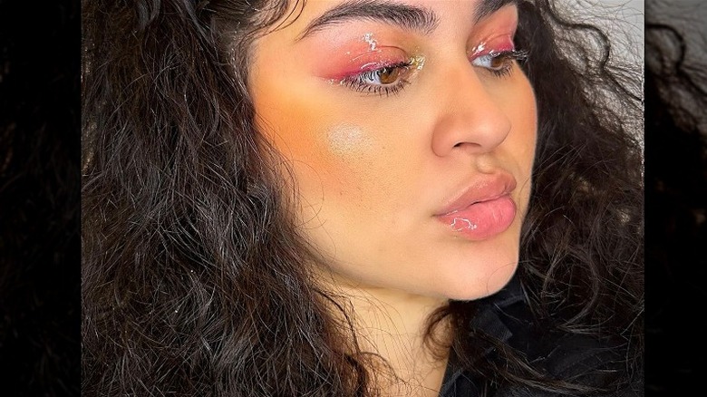 Woman poses wearing eye gloss 