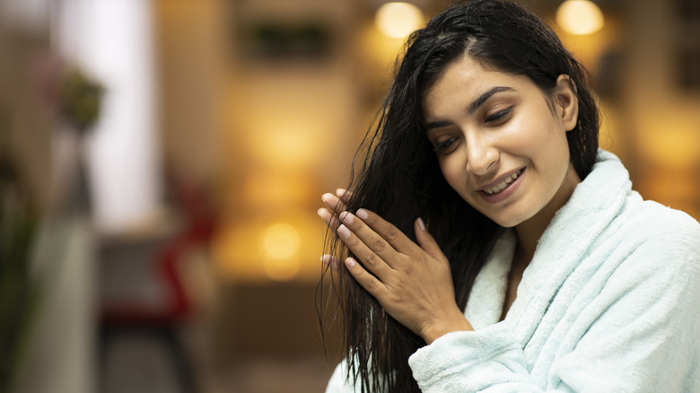 Woman applies serum oil to hair