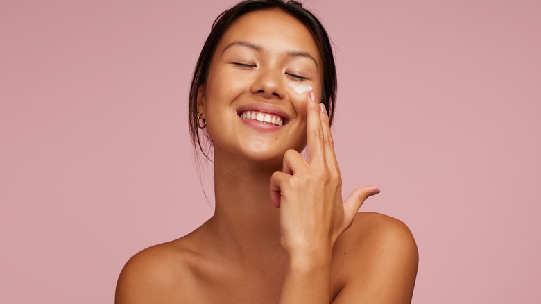 woman applying skincare product on face