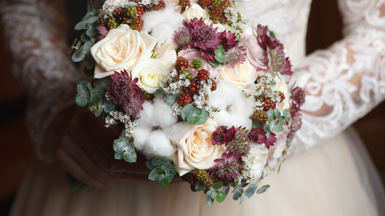 Bride with lace sleeves, holding bouquet