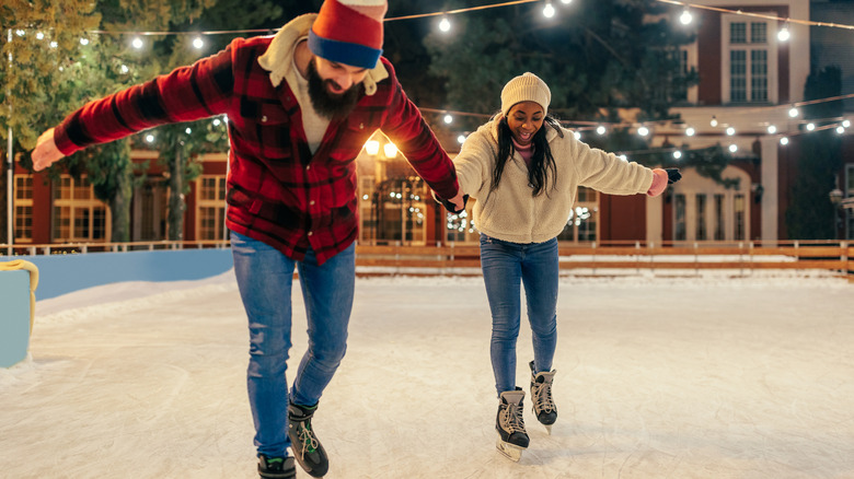 Smiling couple ice skating at night