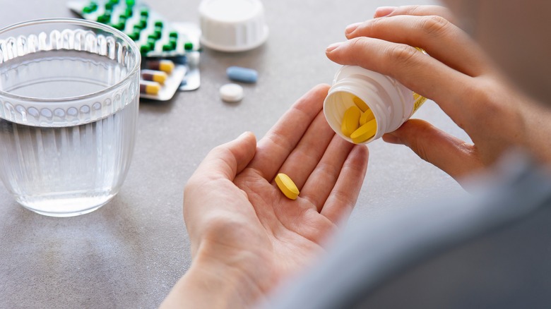 Person taking daily vitamins. 