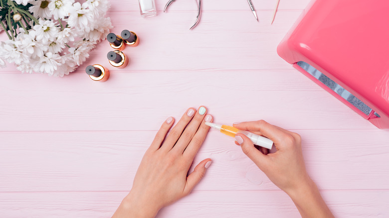woman applying cuticle oil on gel manicure