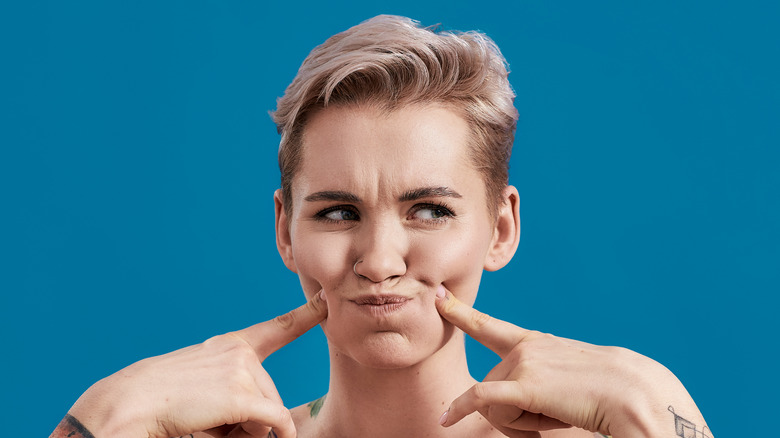 Woman poking cheeks and looking away