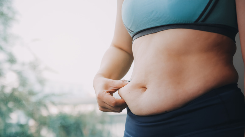 A woman in a crop top grabbing her lower belly