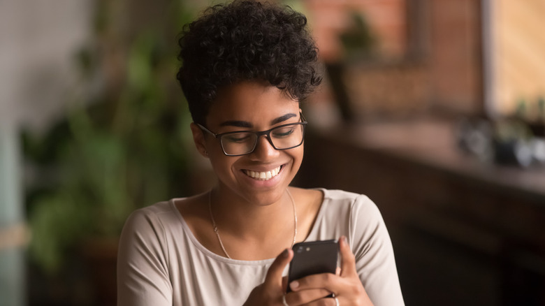 Woman smiling while looking at her phone