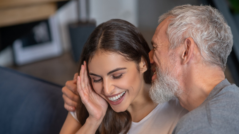 man whispering in womans ear