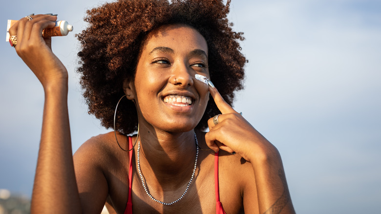 Woman applying sunscreen on cheek
