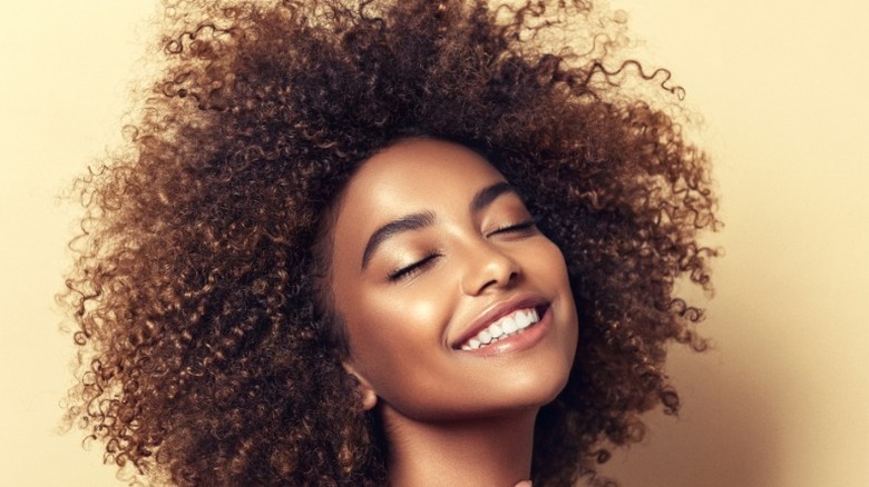 Curly-haired woman smiling in sun