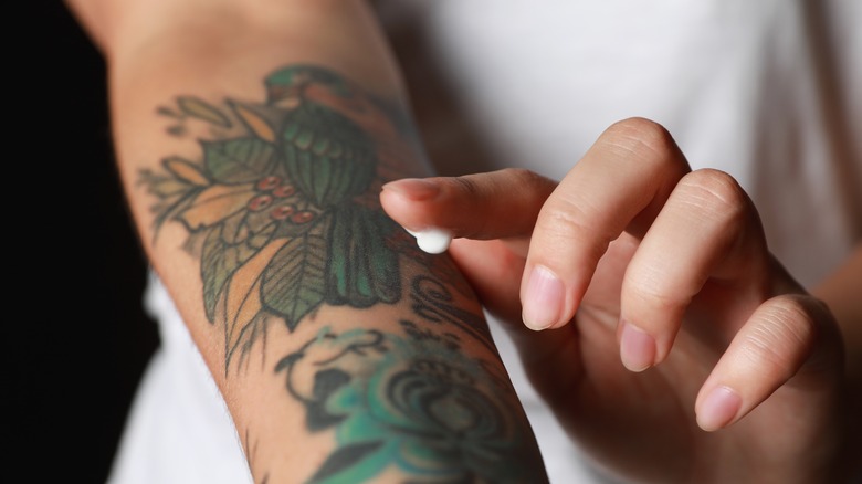 Woman applying lotion to her tattoo